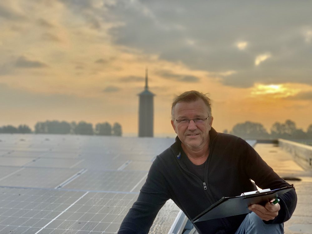 Krijn van Energieke Regio op een dak met zonnepanelen bij zonsondergang